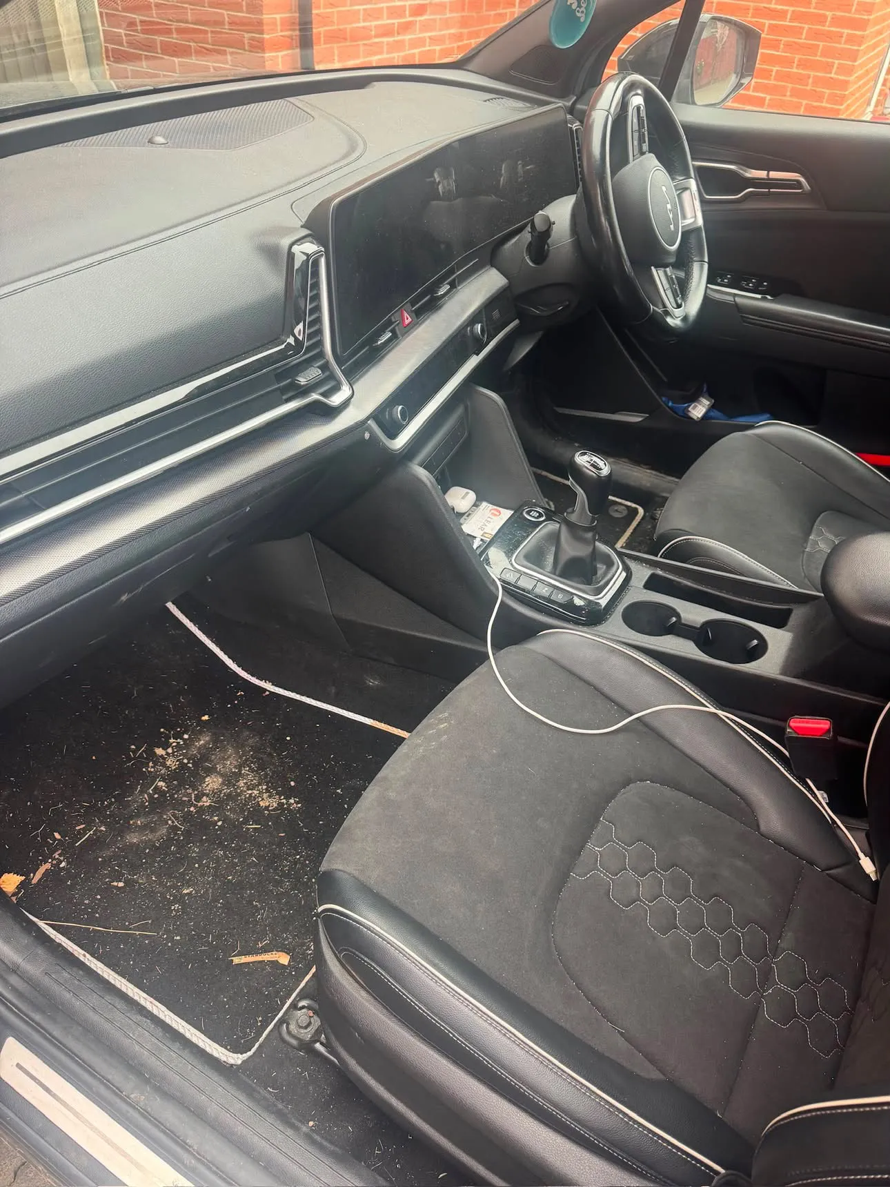 Driver's footwell of the same SUV strewn with debris and dried mud across the mat and sill.