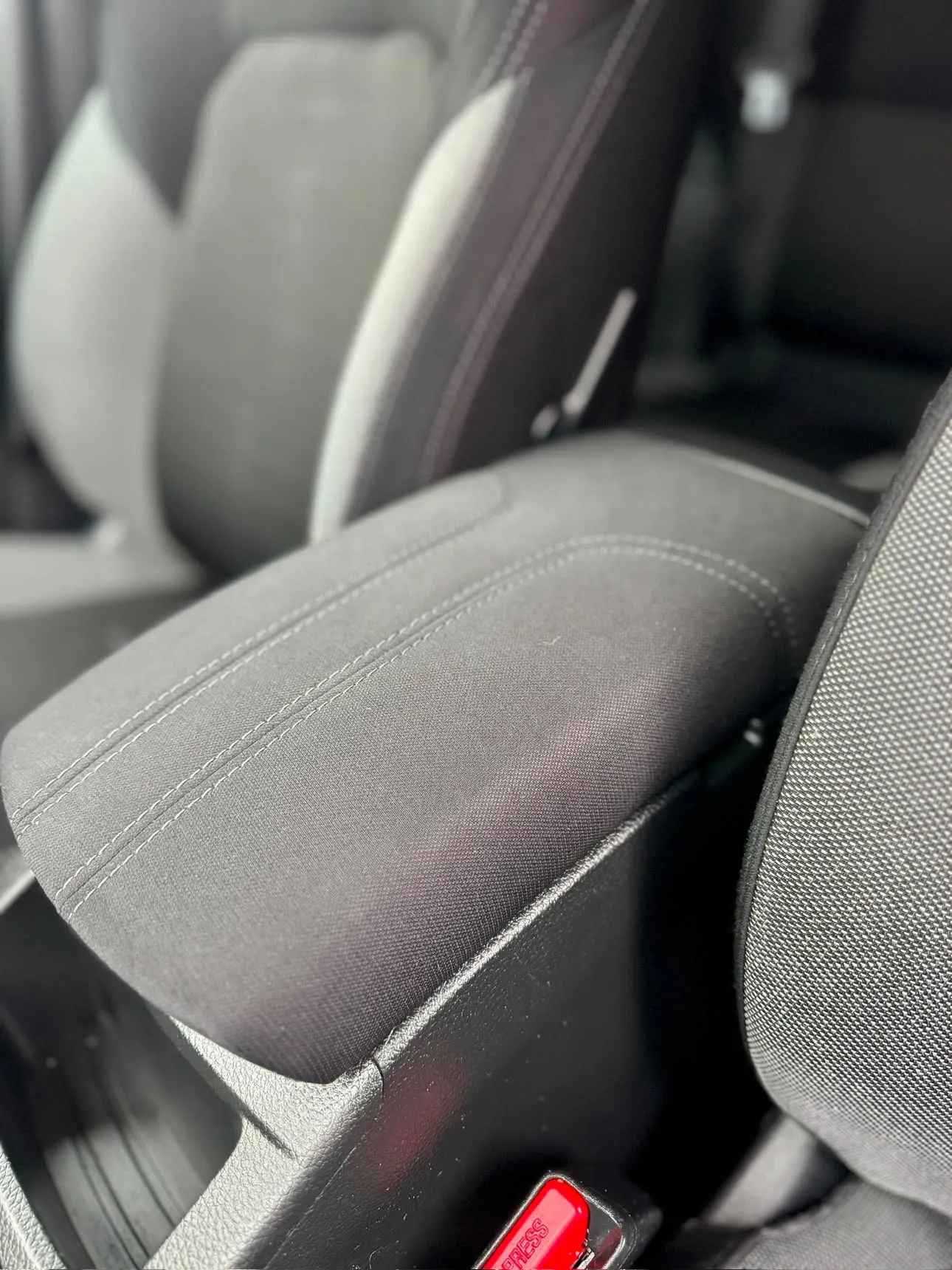 The same armrest cleaned back to plain black fabric with its stitching visible again.