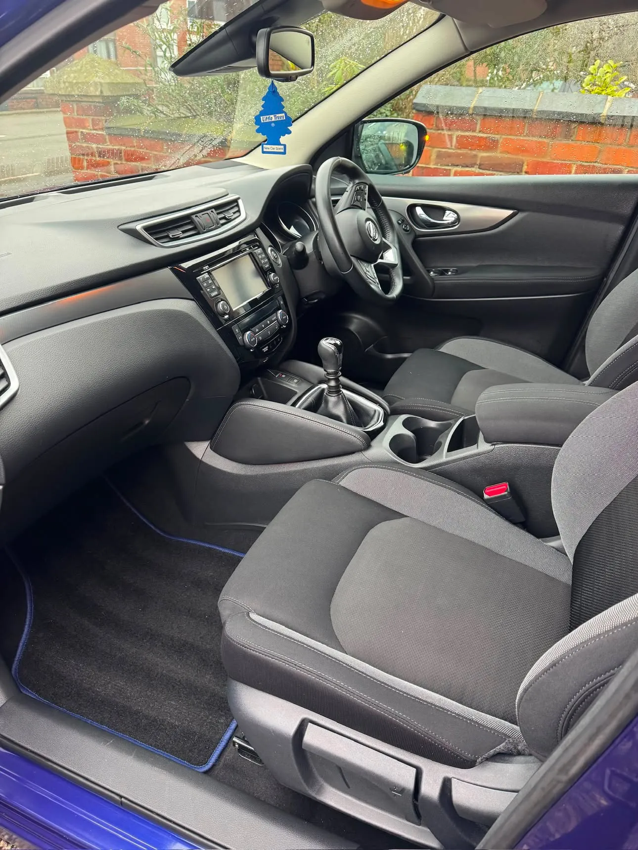 The same front interior finished — seats, console, dash and carpets clean, daylight through the open door.