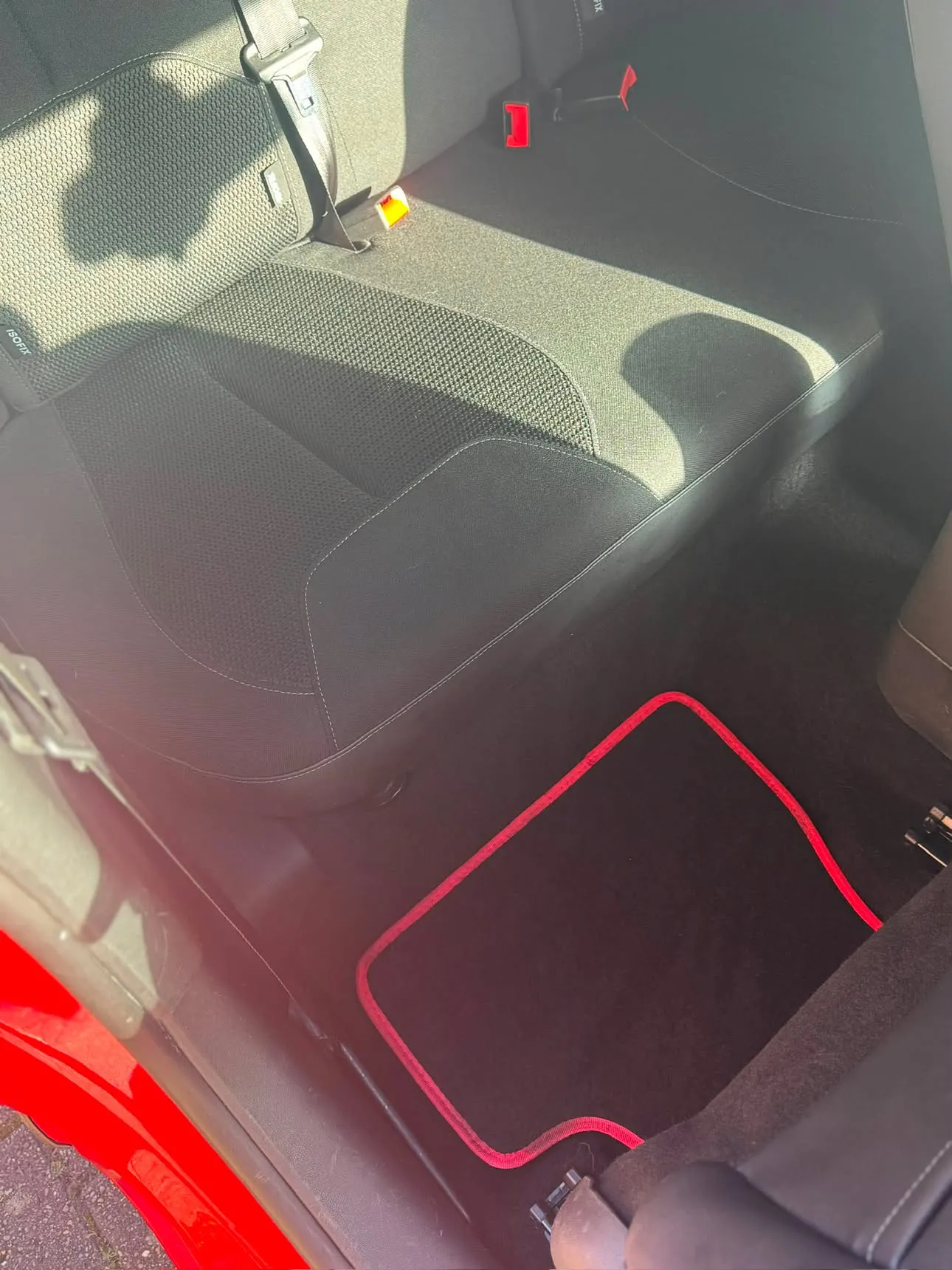 The same rear seats clear of hair, the red-trimmed mat back in place on a vacuumed carpet.