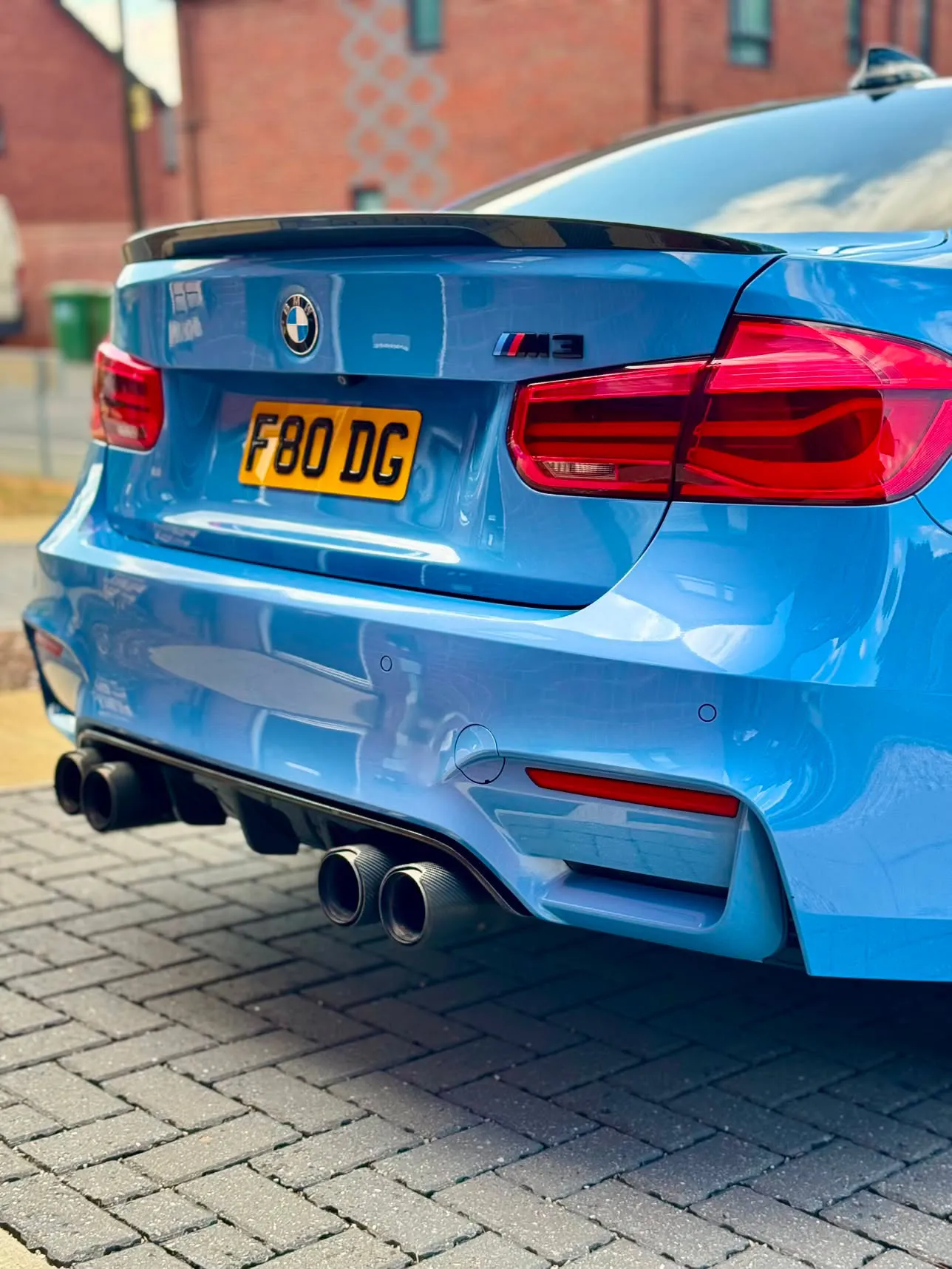 Rear of a Yas Marina blue BMW M3 on block paving, carbon spoiler and quad exhausts, paint deep and glossy after detailing.